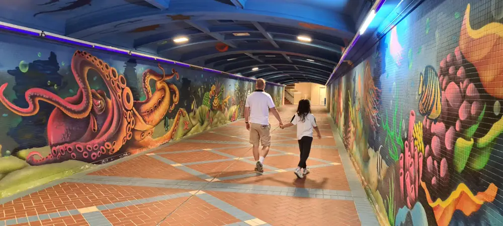 Walking hand in hand through an underpass painted with an undersea mural