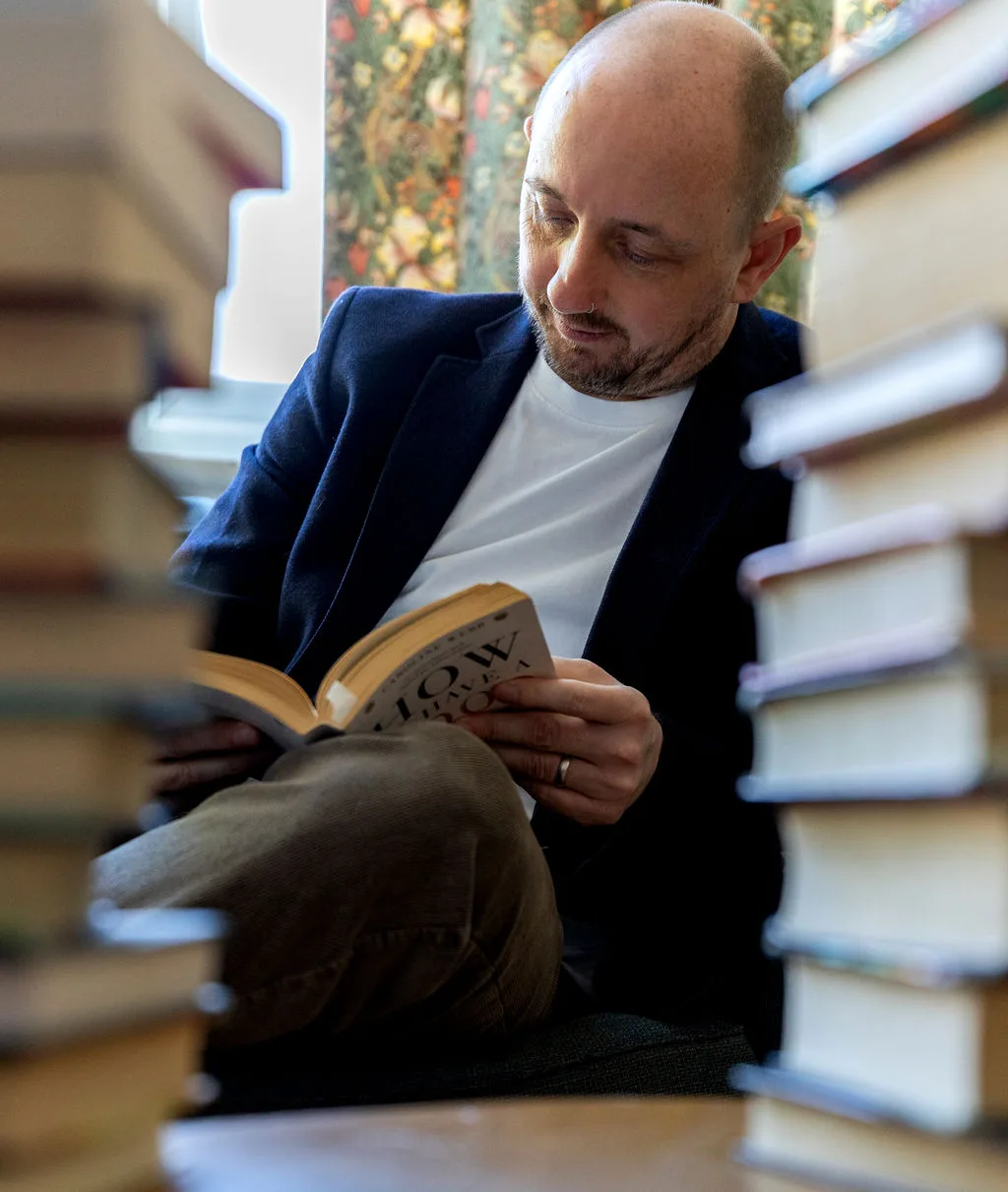 Rob reading surrounded by books